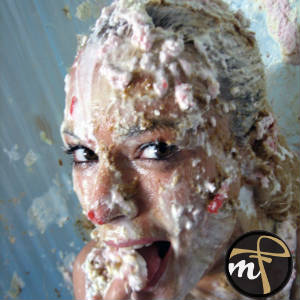 A photo of a woman smeared and covered with pie, cream, cake, and whatever....