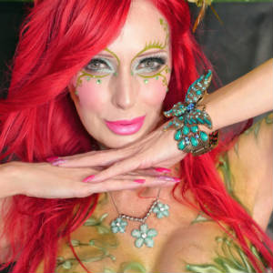 Close Up pho of Shanda Fay is exotic masque makup and plant like ornamentation.