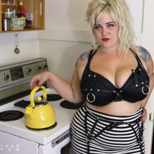A photo of Genevieve Lafleur in costume as a trailer park babe with tight black & white skirt and black leather bra, in a kitchen setting.